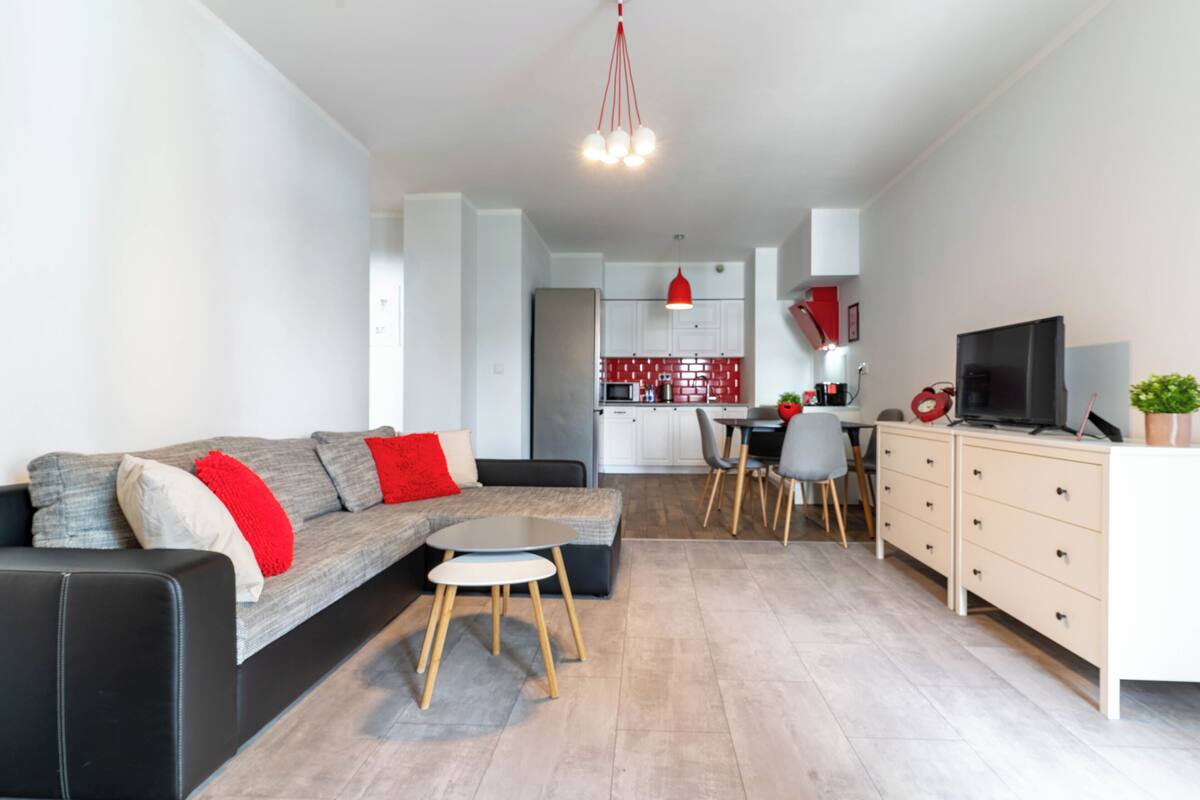 Una sala de estar moderna con un sofá, una mesa de comedor y una cocina al fondo.