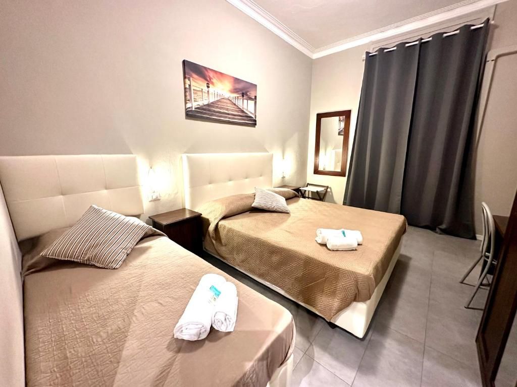 A hotel room with two beds, a nightstand, a mirror, and a painting on the wall.