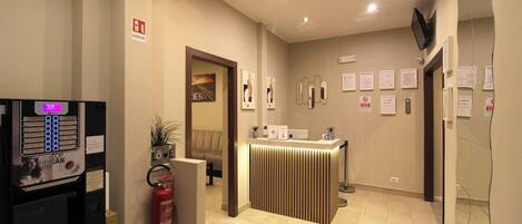 A reception area with a counter, framed certificates, a fire extinguisher, and a vending machine.