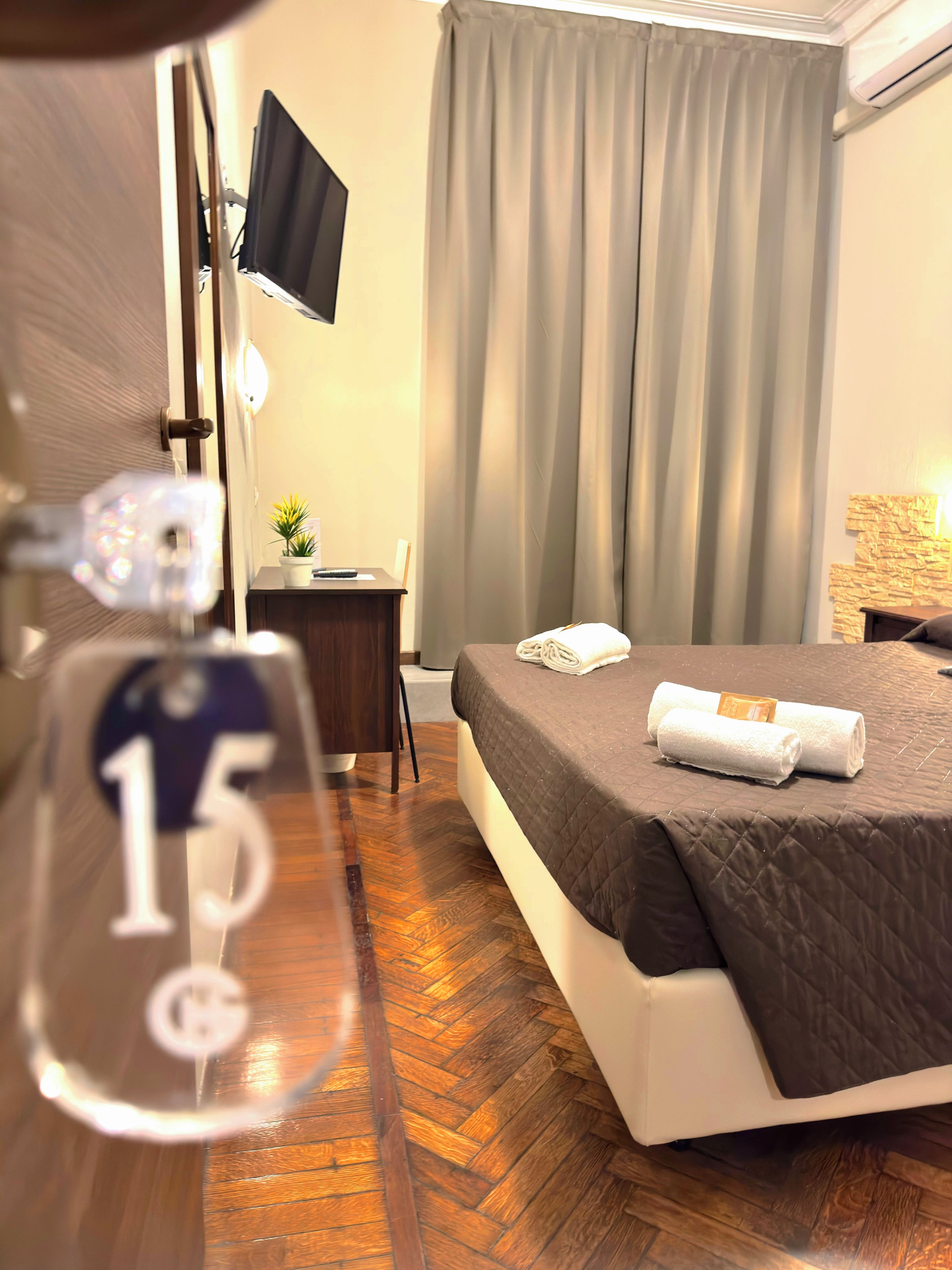 Ein Hotelzimmer mit Bett, Schreibtisch, Fernseher und einem Fenster mit Vorhängen.