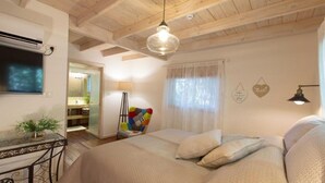 Um quarto aconchegante com uma cama grande, uma escrivaninha com uma planta, uma cadeira colorida e um ventilador de teto.