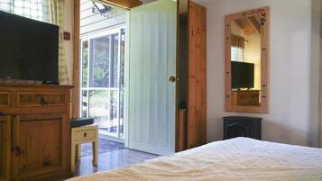A bedroom with a bed, a television, a wooden cabinet, and a sliding glass door leading to an outdoor area.