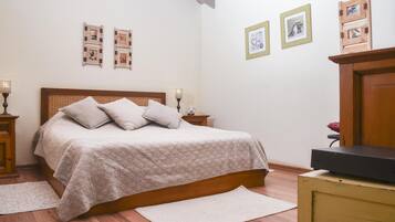 A bedroom with a wooden bed, a nightstand, a dresser, and a wall with framed pictures.
