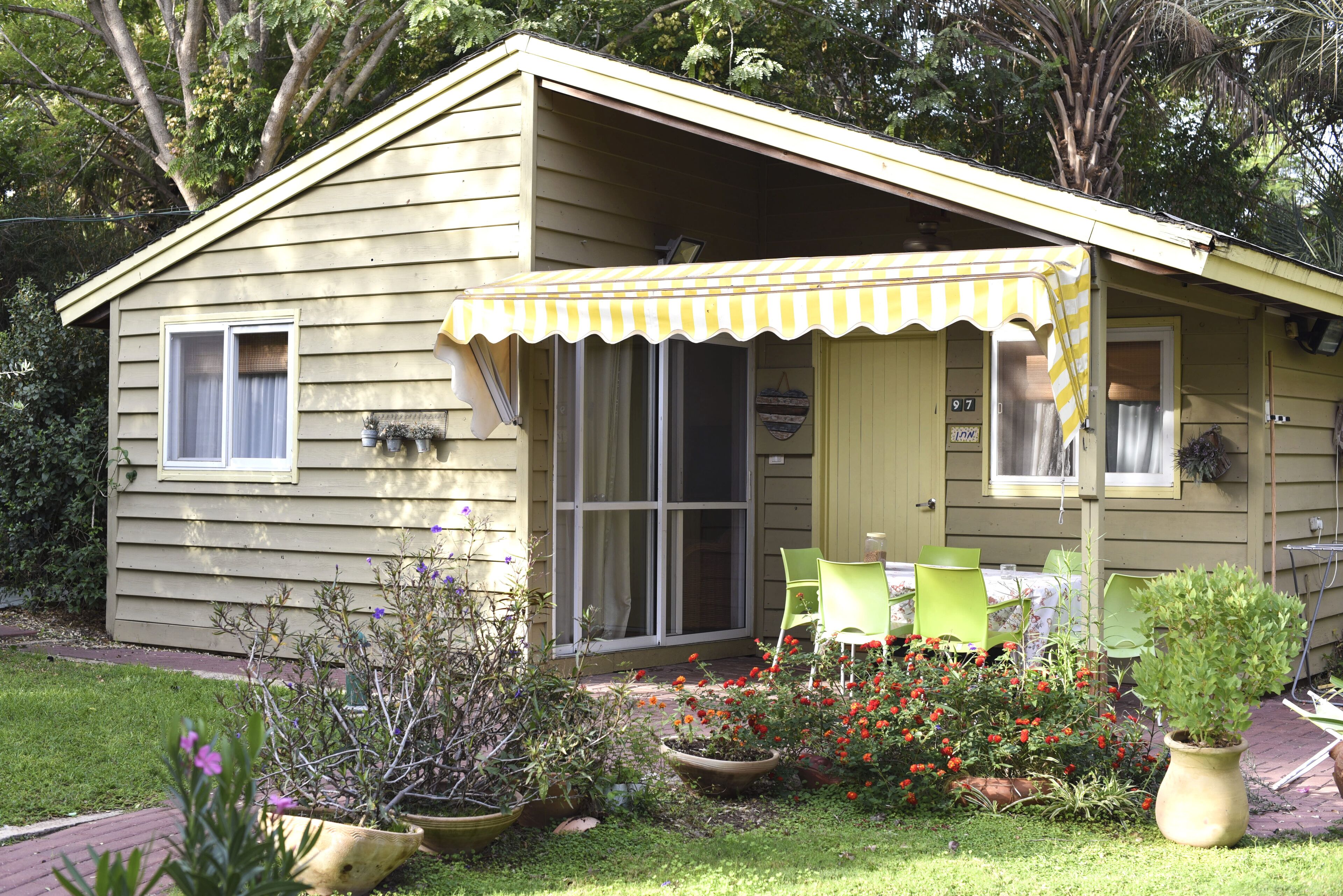 Une maison de plain-pied dotée d’un porche abrité, d’une porte-fenêtre coulissante et d’un petit espace patio aménagé avec des chaises.