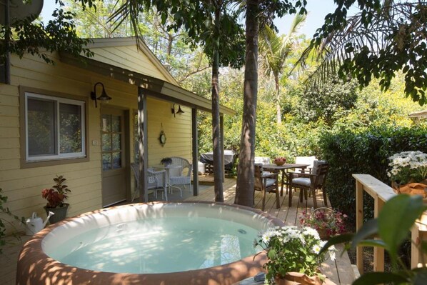 A backyard with a hot tub, a wooden deck, and a covered patio area with outdoor furniture. - Beit Ram Sherf Country Resort (Ramot)