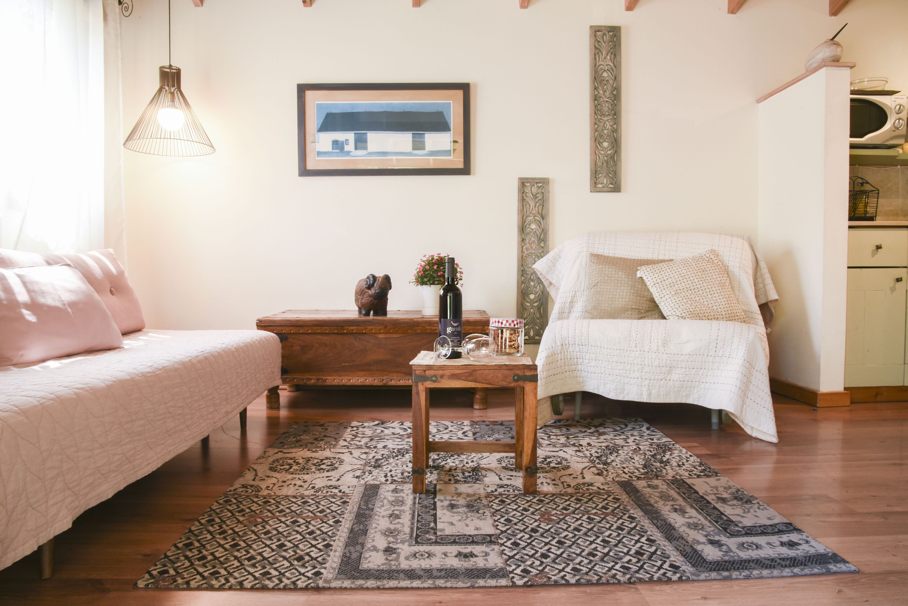 A cozy bedroom with a bed, a chair, a small table with a vase, and a patterned rug.