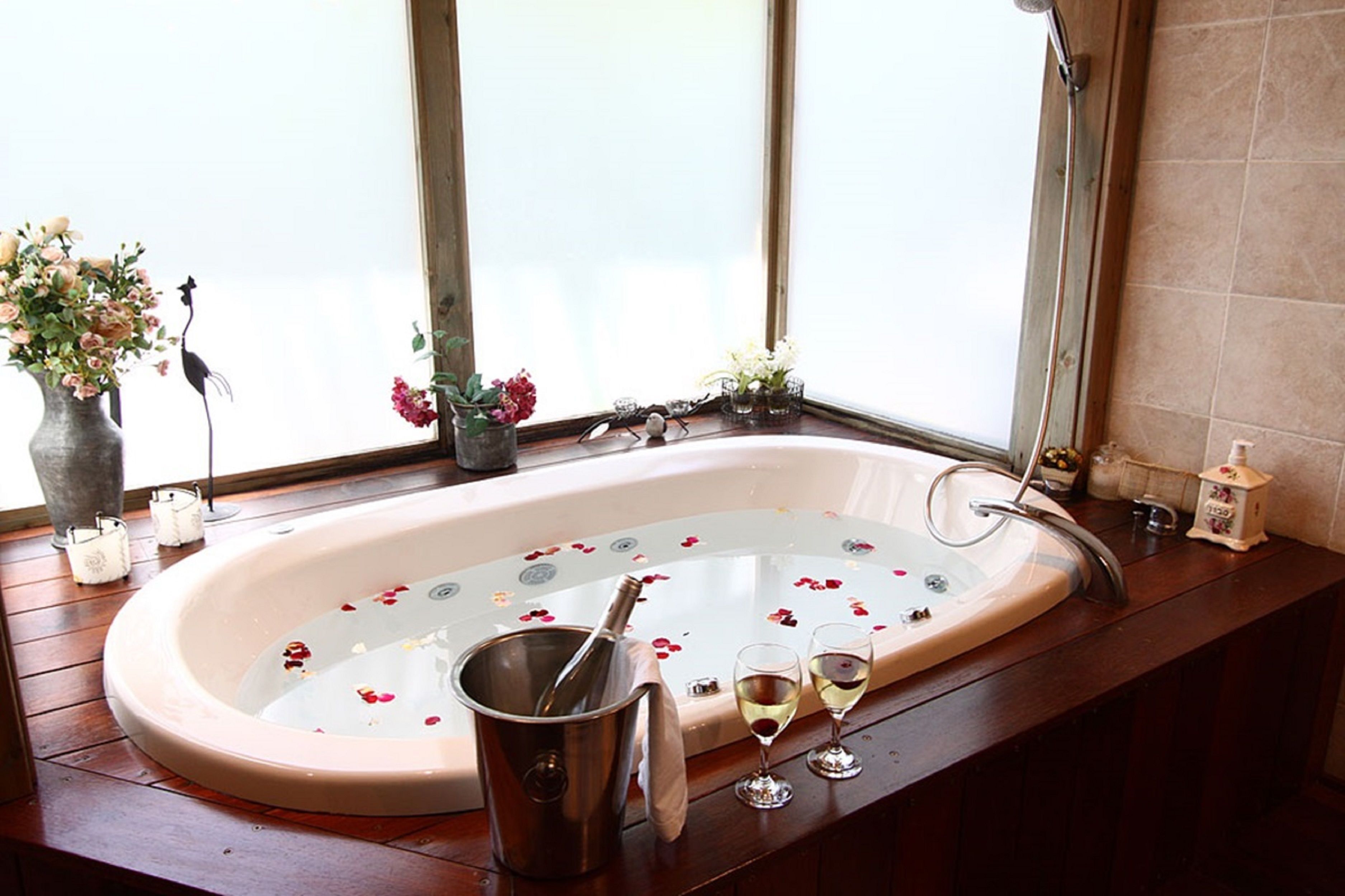 A bathroom with a bathtub, a window, and a wooden vanity.