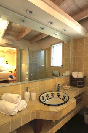 A bathroom with a large mirror, a sink, and a shower area. - Beit Ram Sherf Country Resort (Ramot)