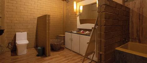A bathroom with a wooden floor, a white toilet, a sink, and a mirror.