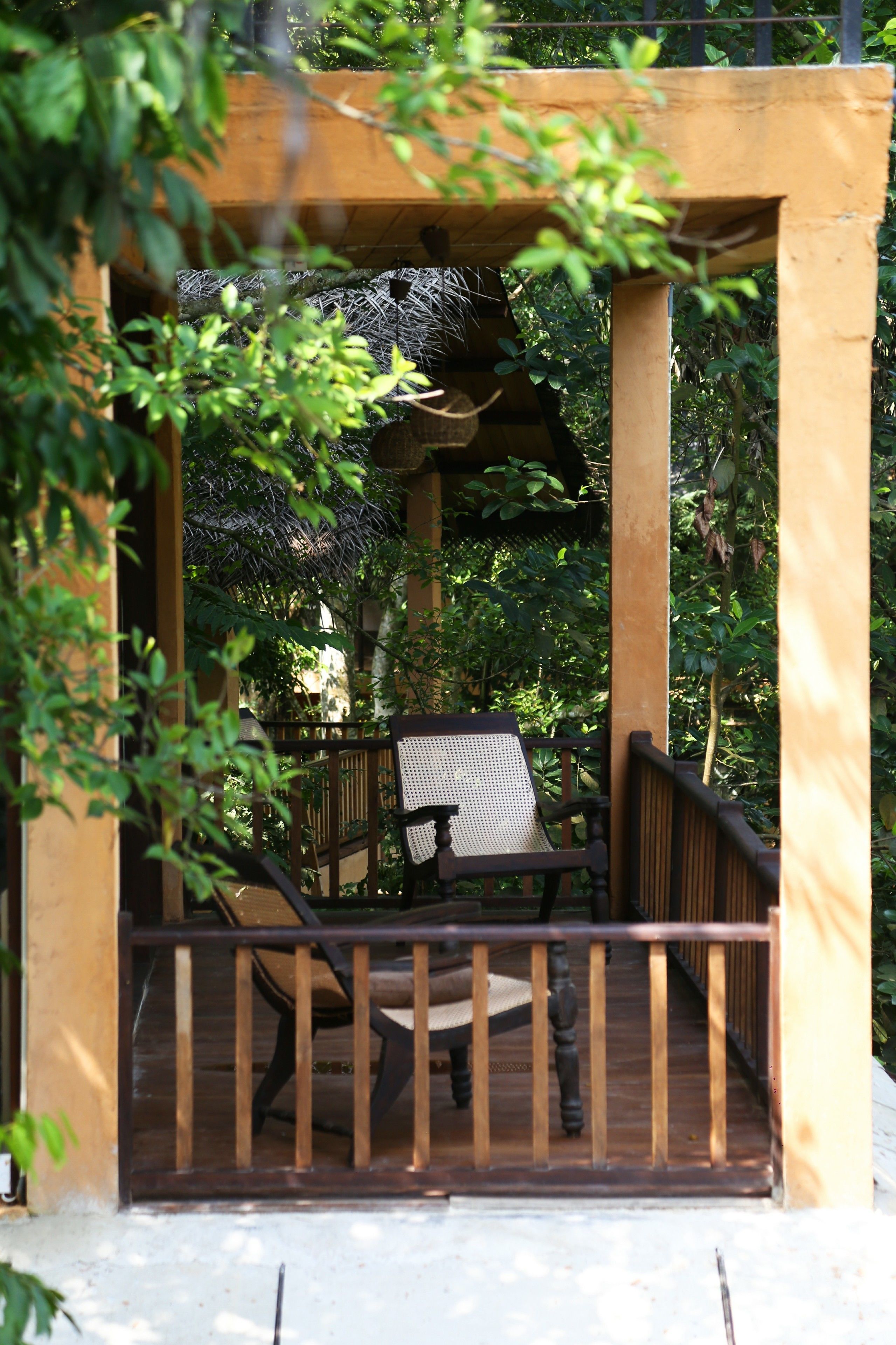 A wooden deck with a bench and a table, surrounded by greenery.