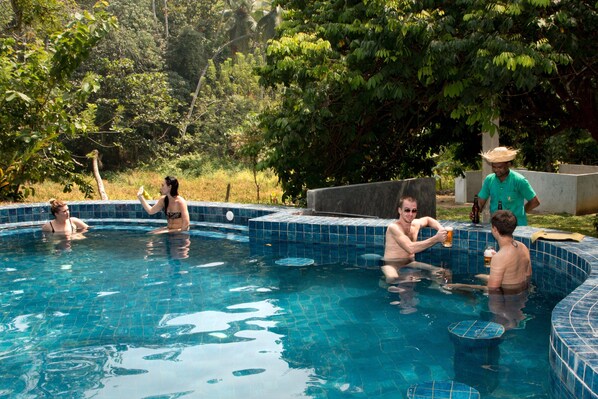 A swimming pool with people relaxing and socializing. - Jungle Village By Thawthisa (Unawatuna)