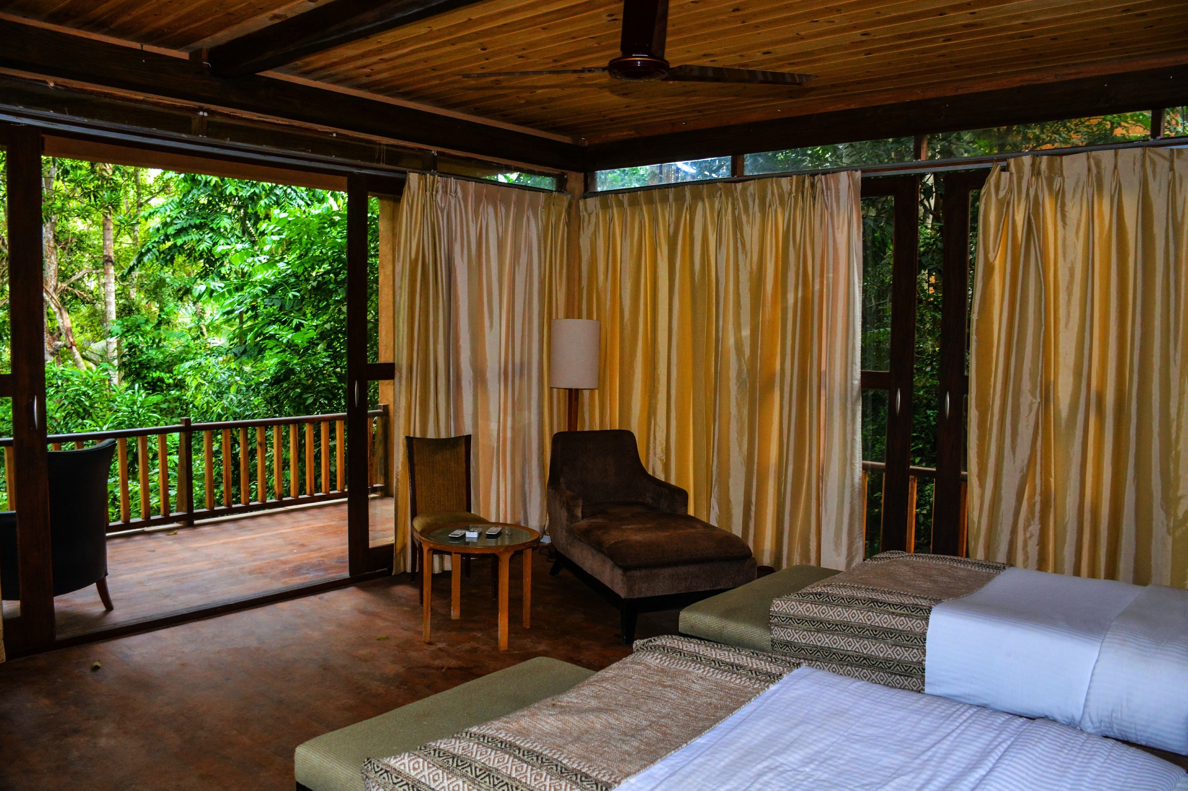 A room with a bed, a chair, a table, and curtains.