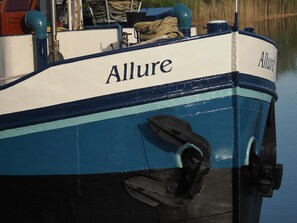 Un bateau appelé « Allure », de couleur bleue et blanche, équipé d’un moteur et de cordes.