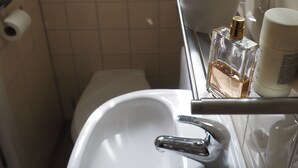 A bathroom with a white sink, a mirror, and toiletries.