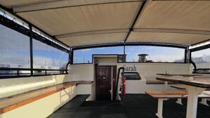 A covered deck area with a wooden bench, a table, and a door labeled "Sarah". - Hotelschip Sarah (Amsterdam)