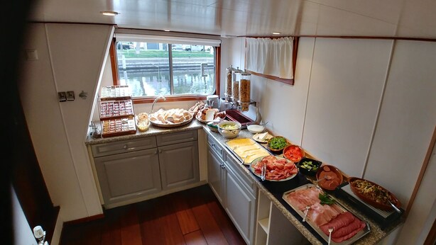 A kitchen with a variety of food items displayed on the counter, including meats, vegetables, and bread. - Hotelschip Sarah (Amsterdam)