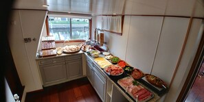 A kitchen with a variety of food items displayed on the counter, including meats, vegetables, and bread. - Hotelschip Sarah (Amsterdam)