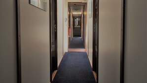 A narrow, well-lit hallway with a carpeted floor, leading to a door at the end. - Hotelschip Sarah (Amsterdam)