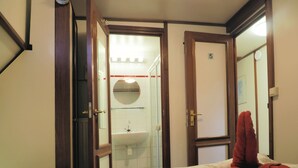 A hotel room with a bed, a bathroom visible through an open door, and a red towel on the bed. - Hotelschip Sarah (Amsterdam)