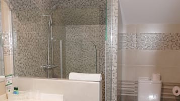 Un baño moderno con ducha acristalada, lavabo blanco y retrete.