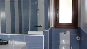 Un baño moderno con un espejo grande, una ducha, un inodoro y un lavabo.