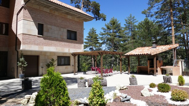 Un bâtiment à deux étages doté d’un patio comprenant un espace extérieur avec des sièges et un coin barbecue.
