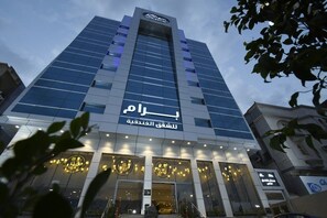 A modern hotel with a prominent sign in Arabic, featuring a glass facade and illuminated entrance. - Bram Hotel Suites (Jeddah)