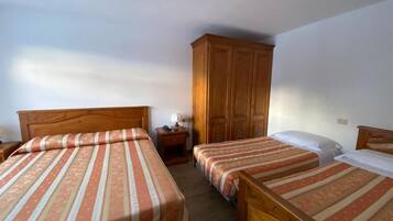 Ein Zimmer mit zwei hölzernen Betten, einem Schrank und einem Nachttisch mit Lampe.