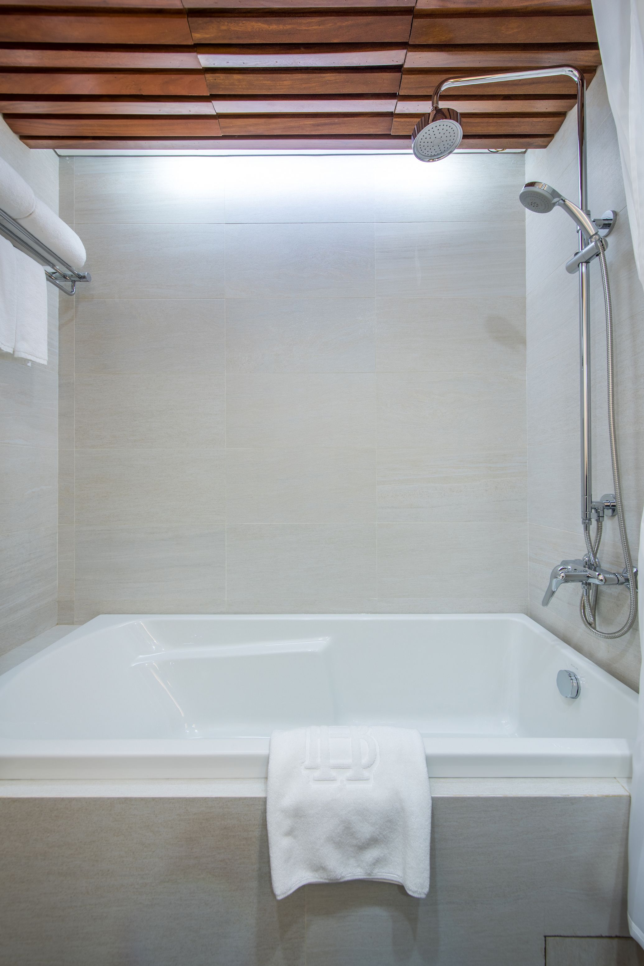 A modern bathroom with a bathtub, shower, and wooden ceiling.