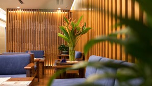 Un área de descanso moderna con paneles de madera, asientos azules y una planta central.
