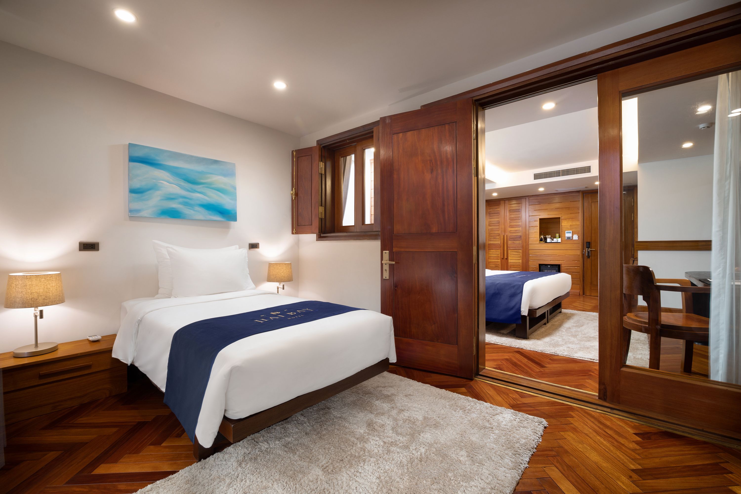 A hotel room with a large bed, wooden wardrobe, and a mirror.