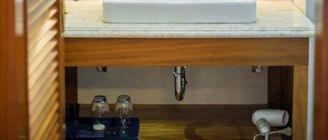 A bathroom with a white sink, wooden vanity, and a mirror above it.