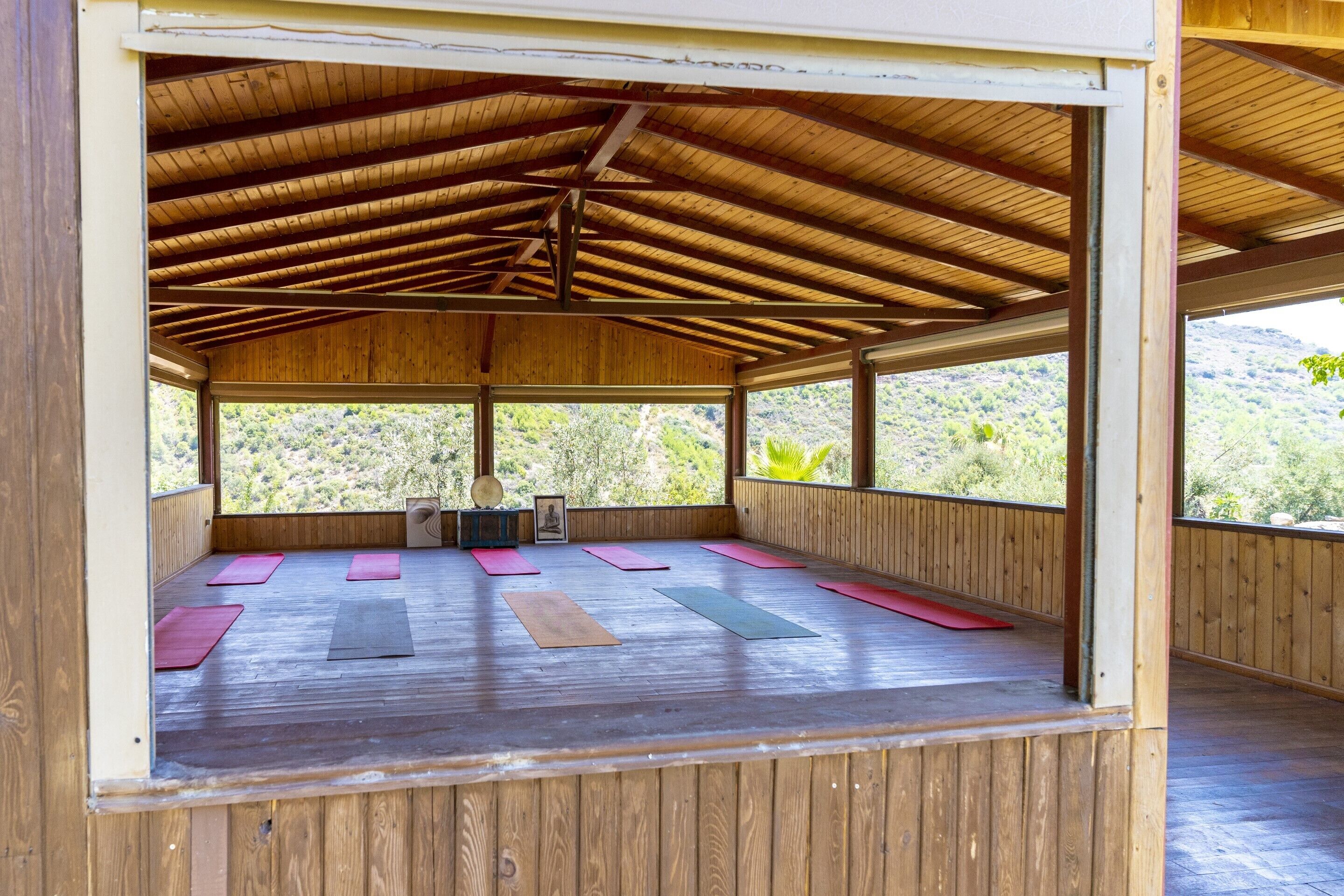 Un espacio al aire libre techado de madera con colchonetas dispuestas para yoga o estiramientos.
