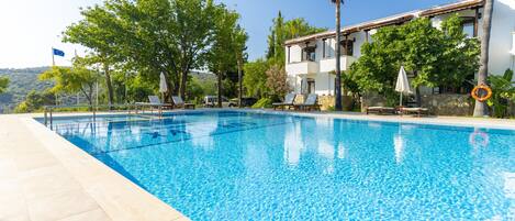 Una piscina al aire libre de temporada, sombrillas