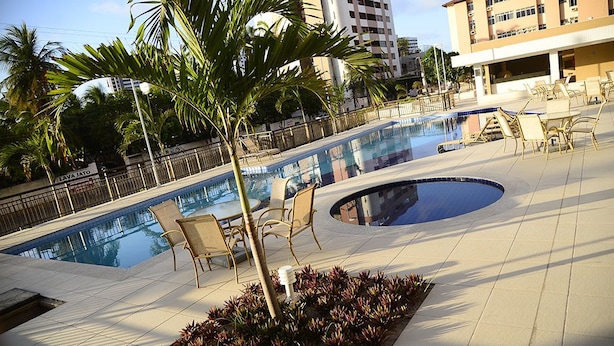 A pool area with lounge chairs, palm trees, and a sign reading "LAVA JATO". - Brooklin Central Park (Fortaleza)