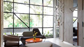 A modern interior with large windows, a sofa, a chair, and a small table with a vase. - ibis Styles Medan Pattimura (Medan)