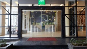 A modern hotel entrance with glass doors, a red carpet, and a sign for 'Ibis Styles'. - ibis Styles Medan Pattimura (Medan)