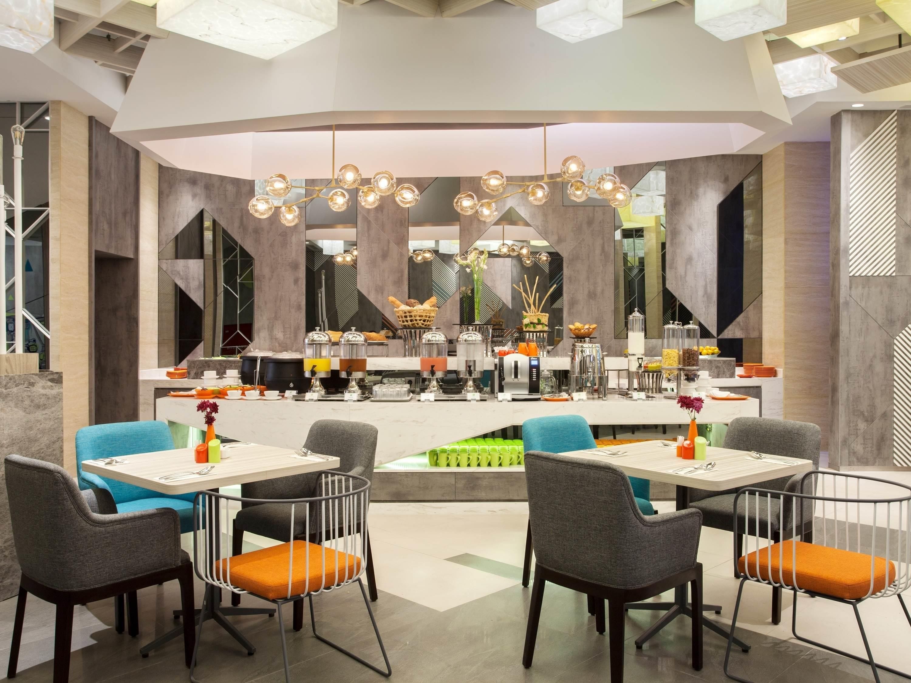 A modern dining area with a central buffet, multiple seating arrangements, and contemporary lighting fixtures.
