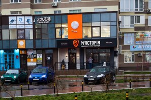 A building with multiple storefronts, including a prominent orange banner for 'MANDURUS' and a sign for 'M'ACTORIA'.