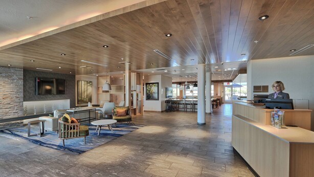 A spacious lobby with a wooden reception desk, comfortable seating areas, and a stone accent wall. - Fairfield Inn & Suites by Marriott Albuquerque North (Albuquerque)