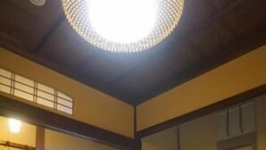 Um quarto japonês tradicional com piso de tatame, uma mesa de madeira, uma porta deslizante e uma janela com cortinas.