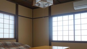 Um quarto japonês tradicional com piso de tatame, uma mesa de madeira baixa e painéis shoji.