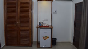 A room with a wooden wardrobe, a small refrigerator with a fresh produce design, a mirror, and a wall-mounted air conditioner. - Chukwani Executive Inn (Zanzibar Town)