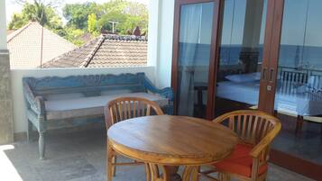 Una mesa y un banco de madera en una habitación con vistas a un tejado de baldosas y vegetación exterior.