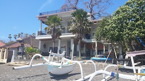 A beachfront property with a boat docked in front, a balcony, and a view of the sea. - Amed Beach Villa (Karangasem)