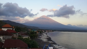 A coastal village with houses along the beach, boats docked, and a mountain in the background. - Amed Beach Villa (Karangasem)