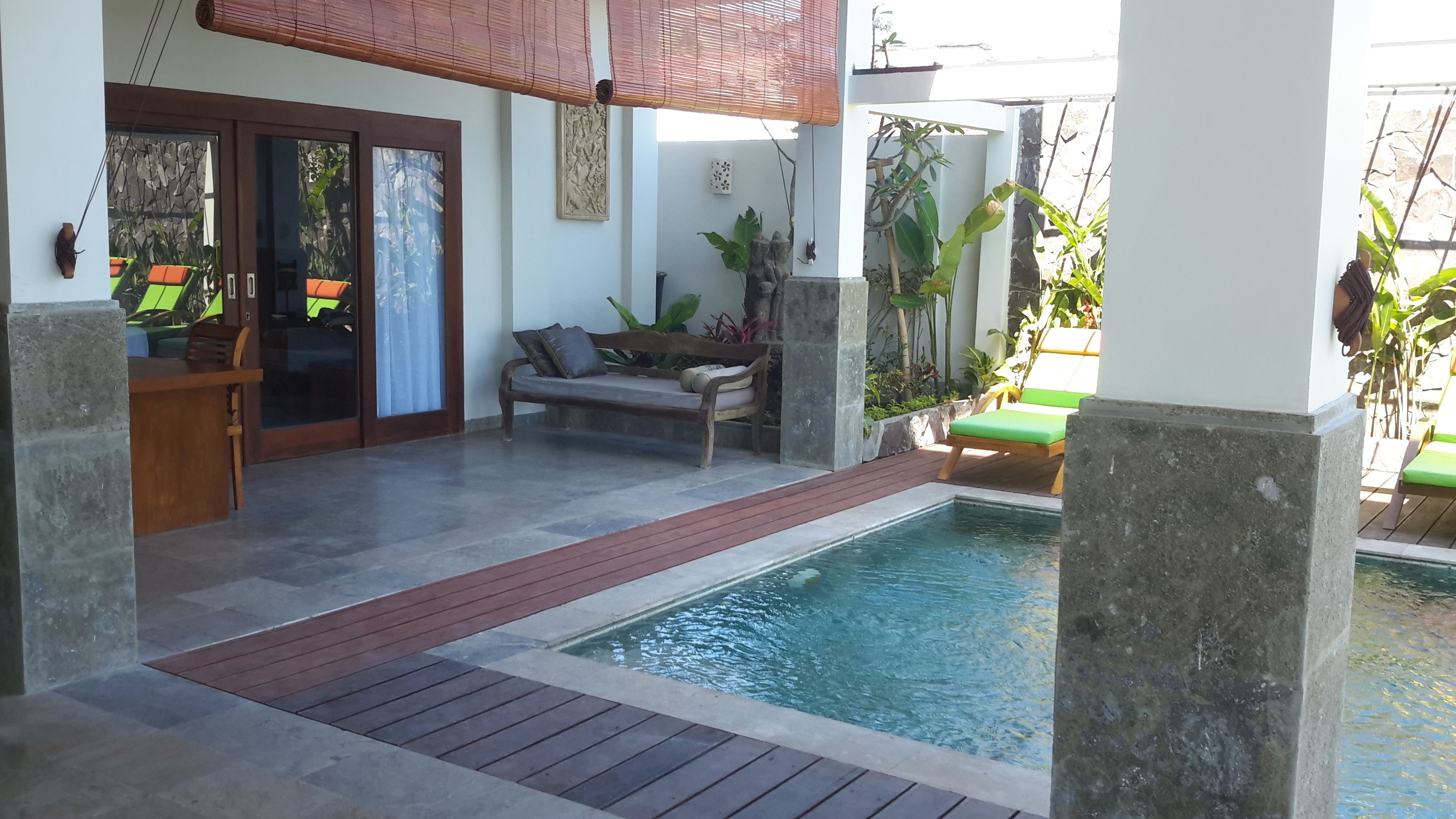 A pool area with a wooden deck, a bench, and a small table.