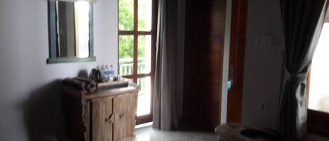 Una habitación con un armario de madera, un espejo y una puerta que da al exterior.