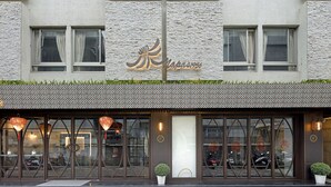 A building with a modern architectural style, featuring a textured facade, large windows, and a prominent logo on the front. - Napas Hotel (Taichung)