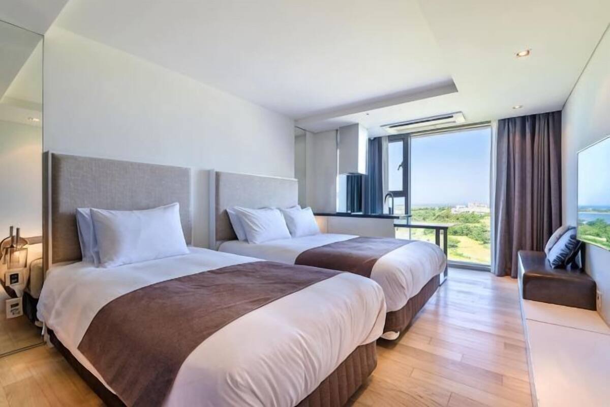 Ein Hotelzimmer mit zwei Betten, einem großen Fenster und einem Balkon.